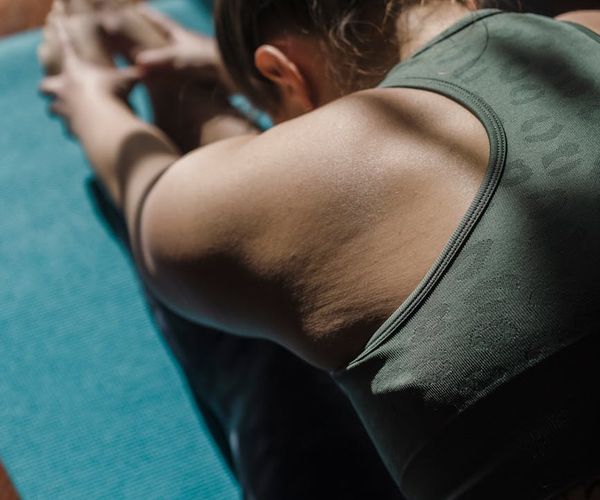 Close up of hands stretching in a yoga position on a dark mat.