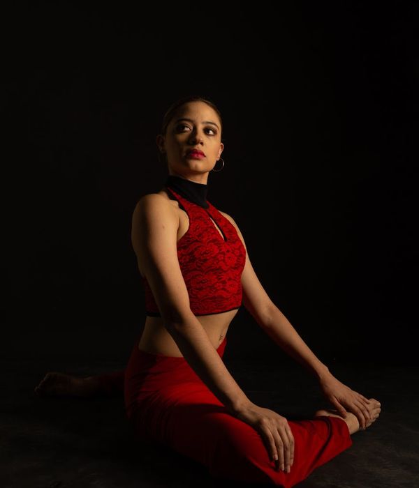 Woman performing a graceful yoga balance pose in a dark studio with azure highlights.